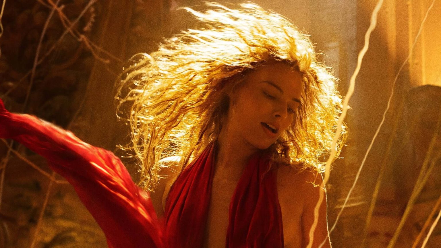 A movie star flicks their long hair, backlit by a strong light