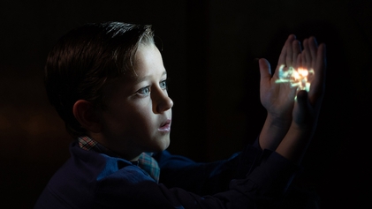 A cinematic view of a child holding an image that lights up their face.