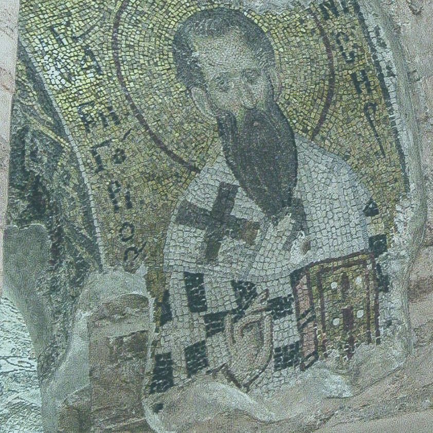 A mosaic shows a saint with a beard holding a bible and his hand held up in a blessing.