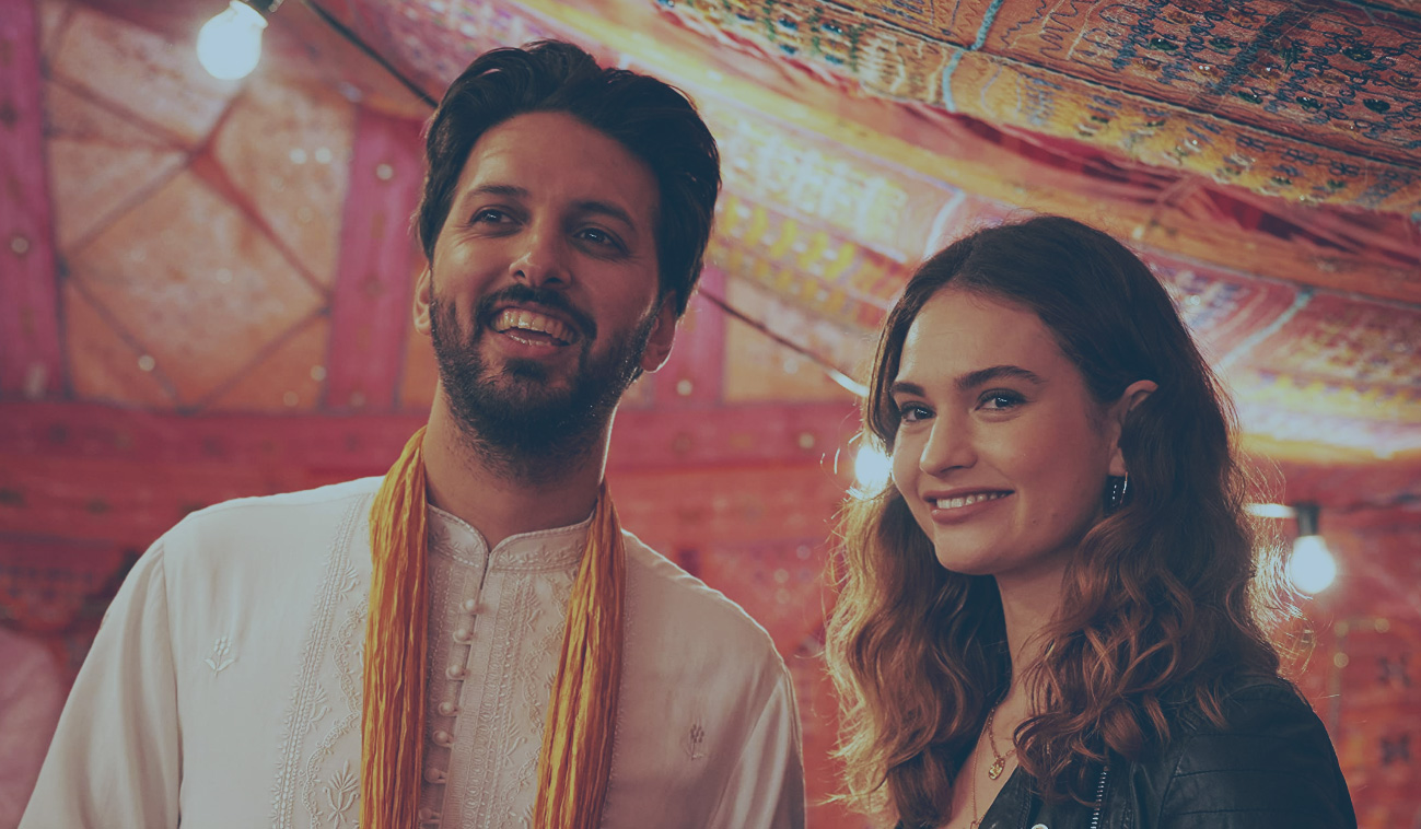 A couple stand and smile at a Pakistani wedding celebration.