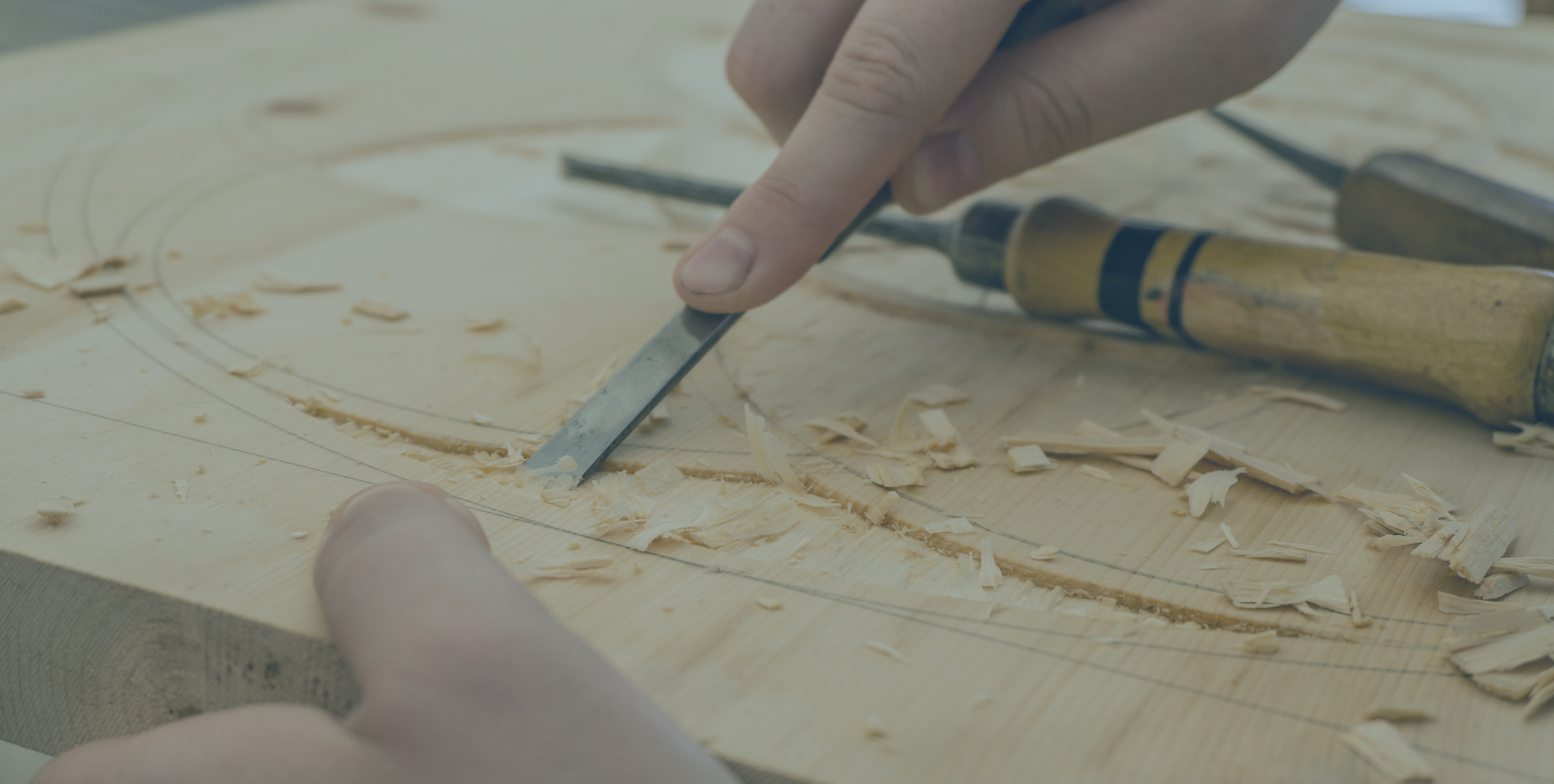 A carving tool is pressed into a groove in wood.