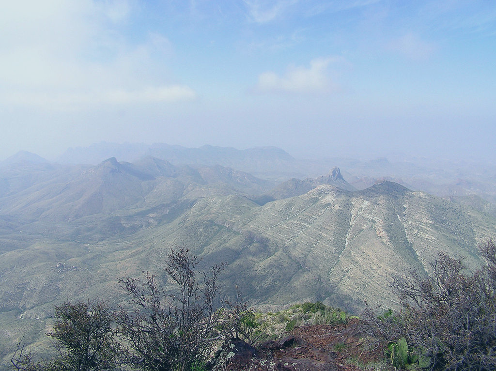 A view of a lightly misted valley to mountains in a desert area.