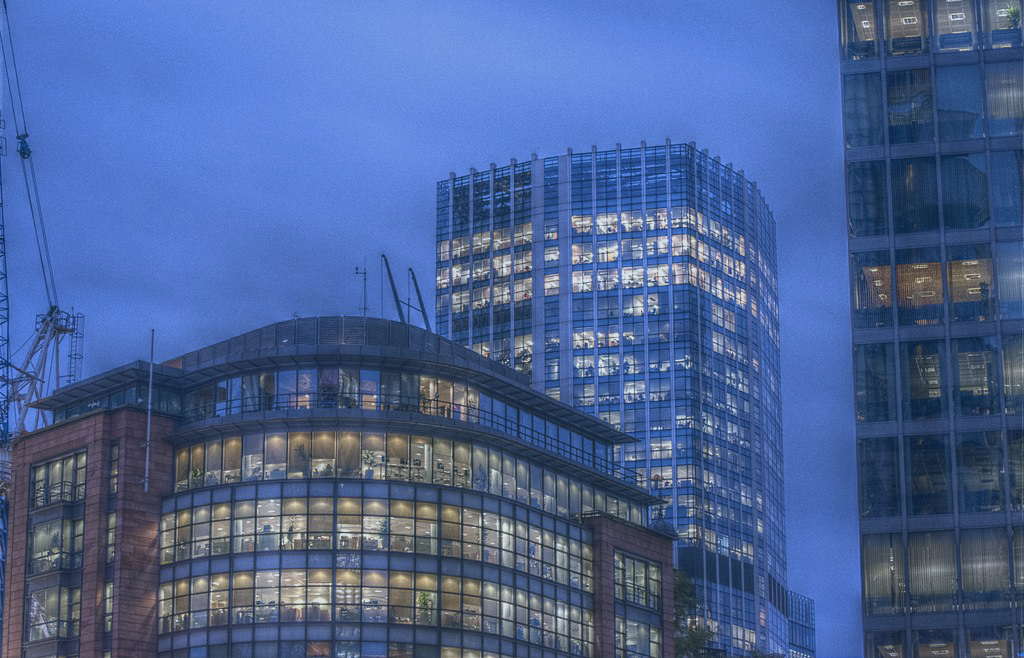 At twlight, the lit office windows of two tower blocks contrast with a darkening sky