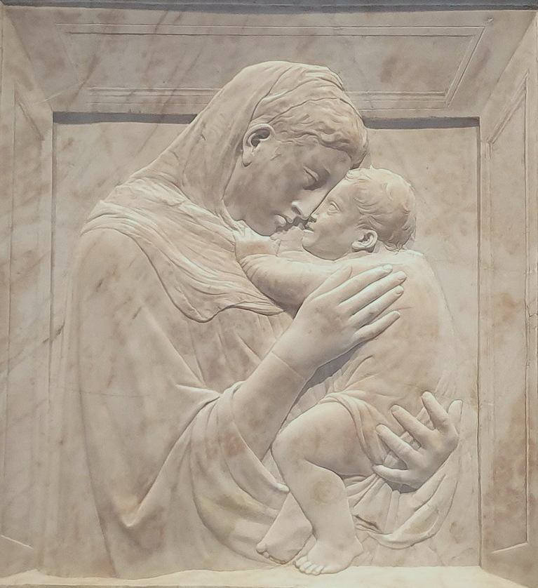 A relief sculpture shows the Madonna hold the infant Christ close to her face.