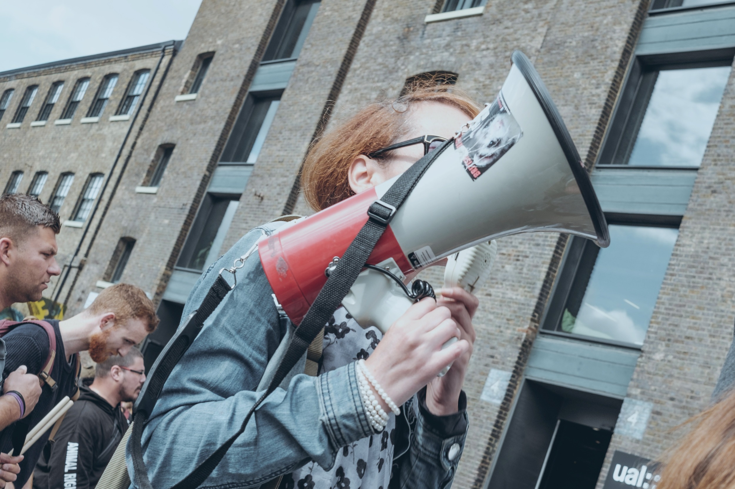 A protestor hold a megaphone up at a demonstration outside a building