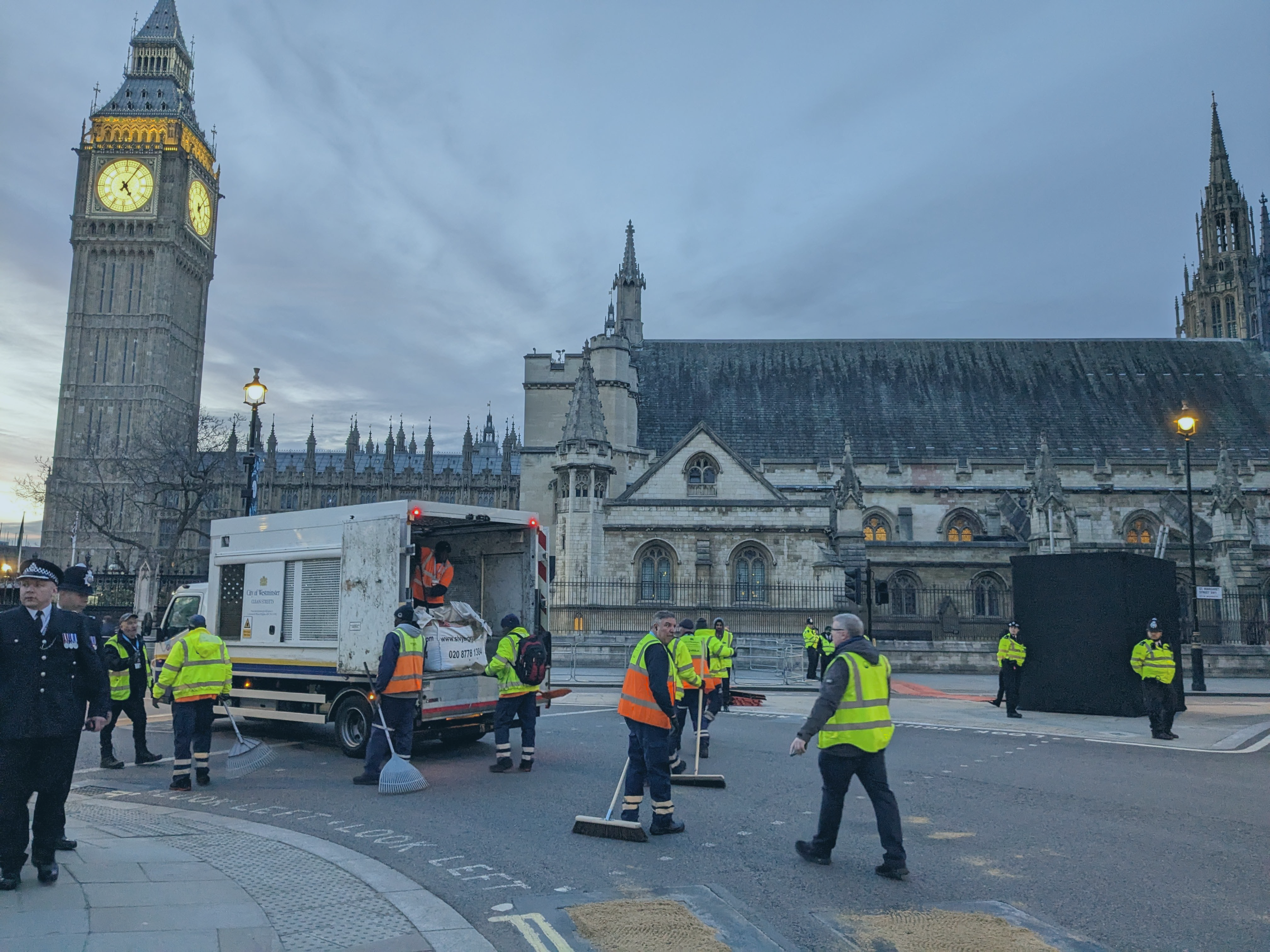 A team of street sweepers clear up the road after the coronation procession, outside the Houses of Parliament.