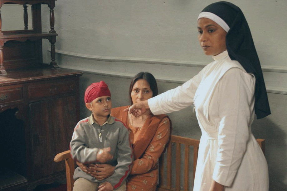 A standing nun points towards a seated mother and child.