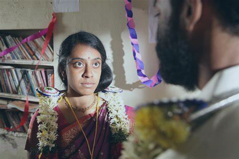 A woman in a classroom stares intensely at a person in front of us.