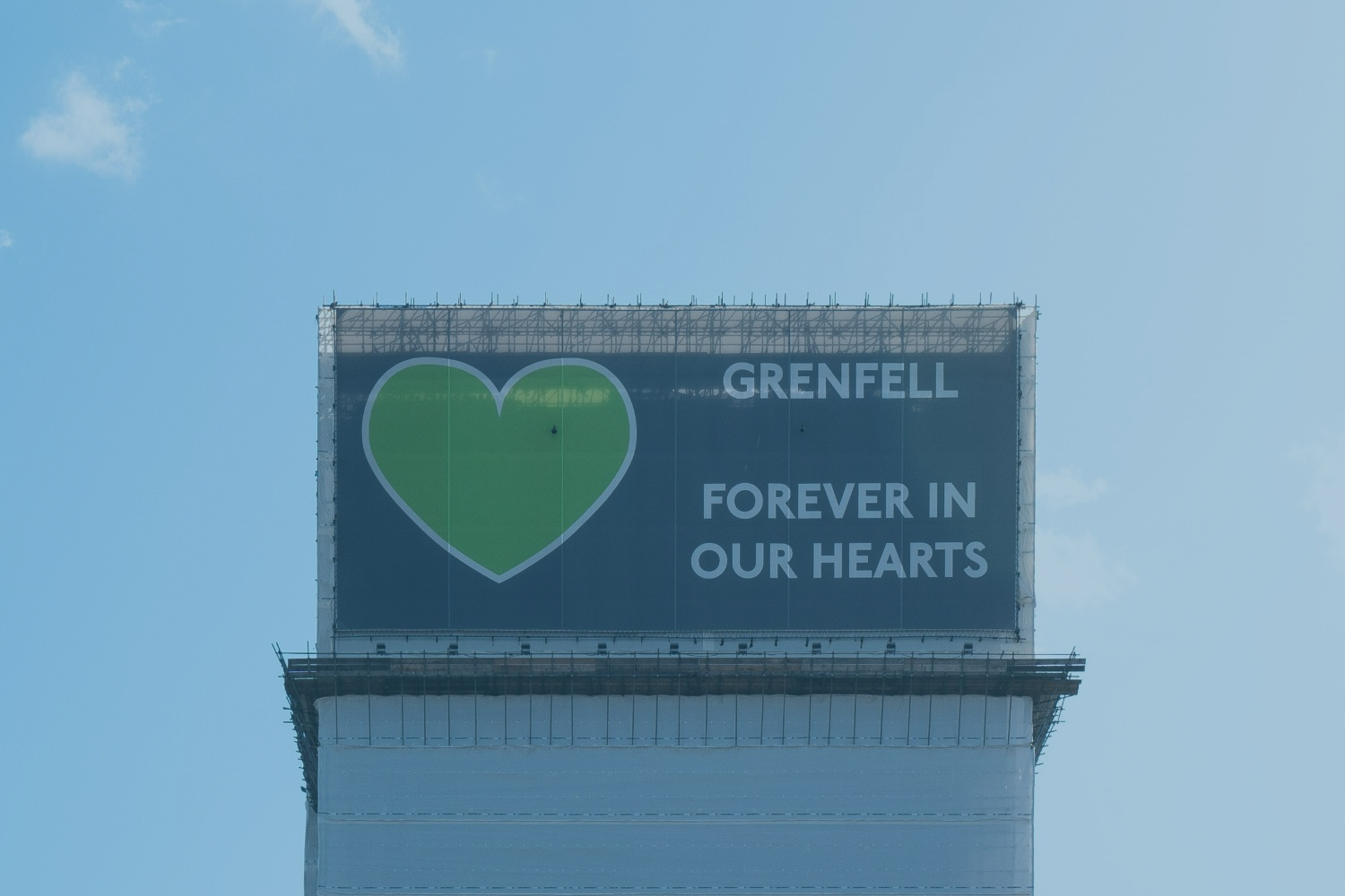 Grenfell Tower, wrapped in a protective layer bearing the legend: Grenfell forever in our hearts