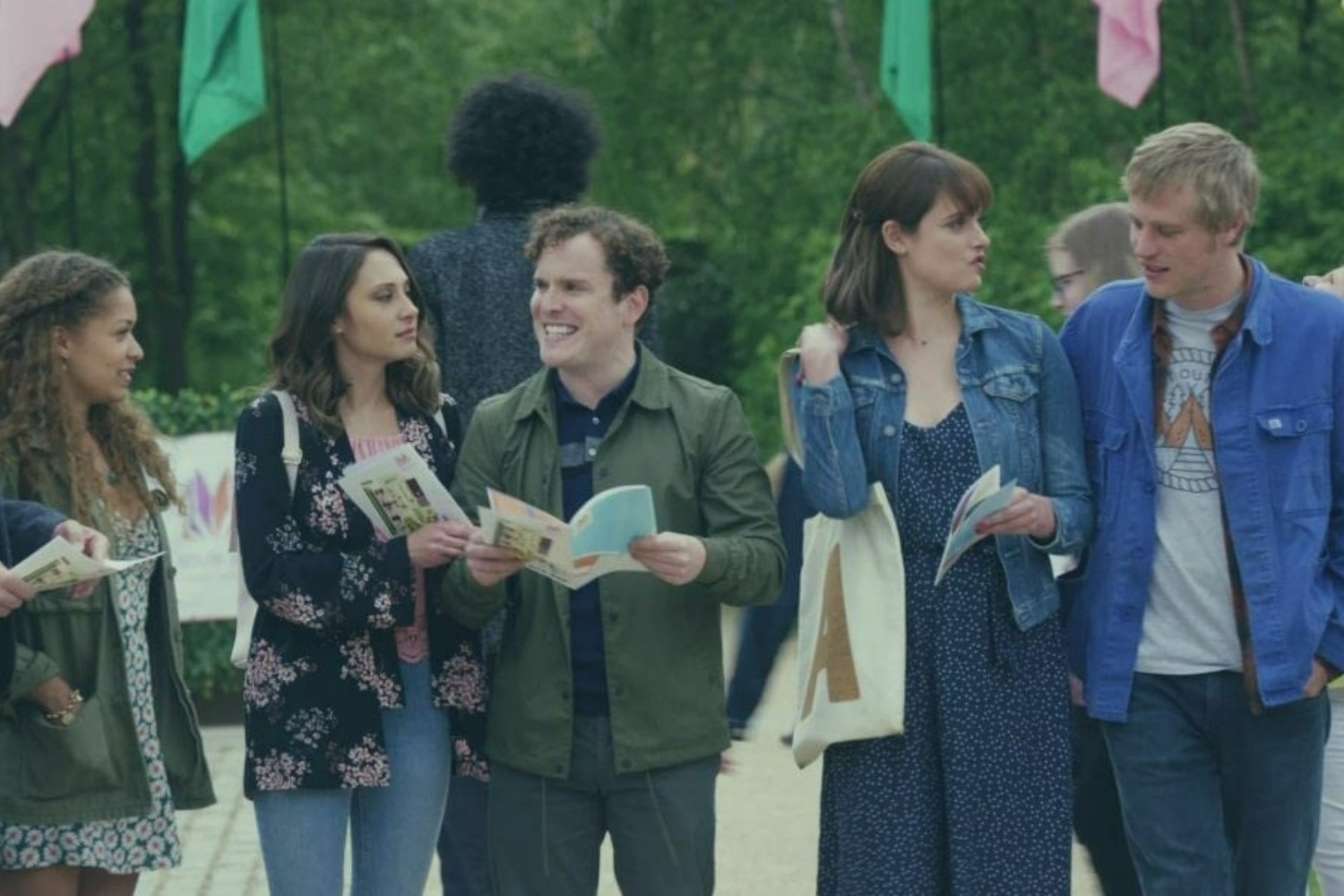 A row of young people stand and talk to each other