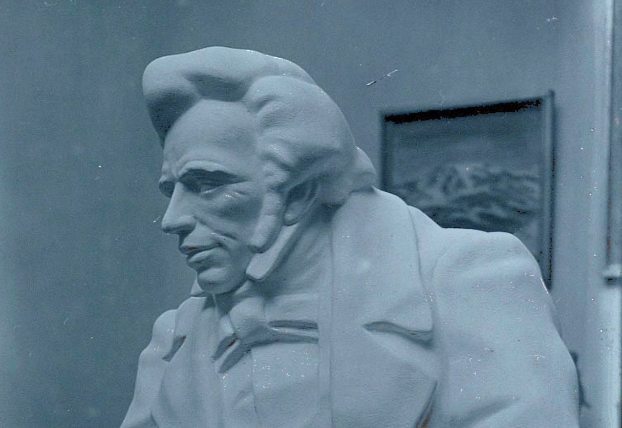 A sculpture of a early 19th century man with a quiff and sharp suit.