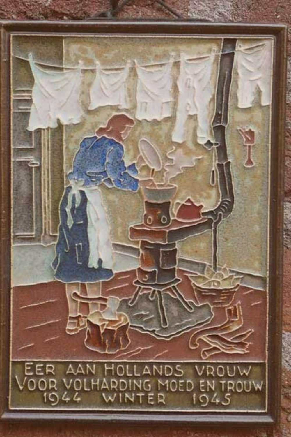 A wall tile shows a 1940s woman tend a stove below a washing line.