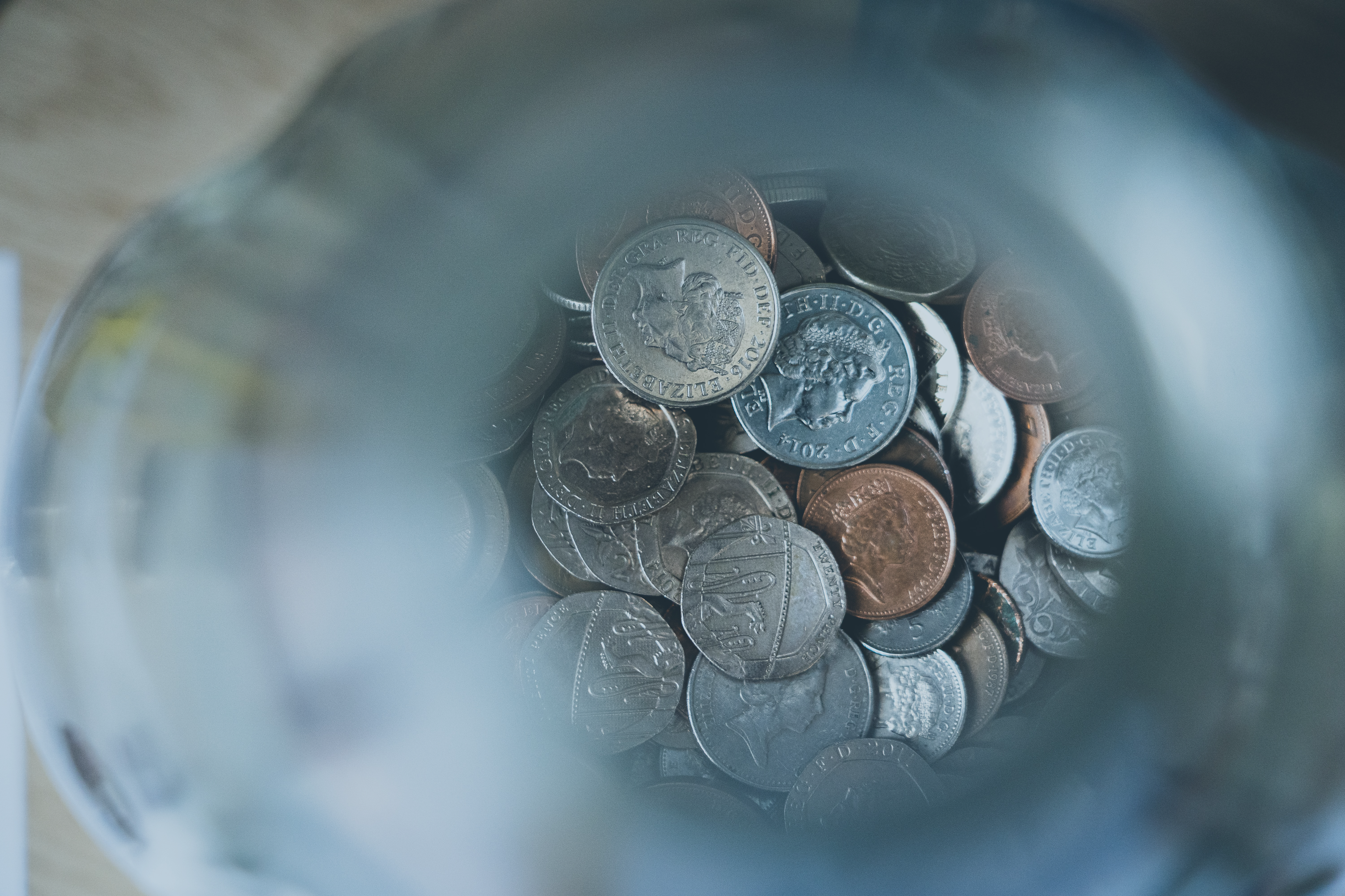 A pile of coins in focus at the bottom of an out of focus glass tube.