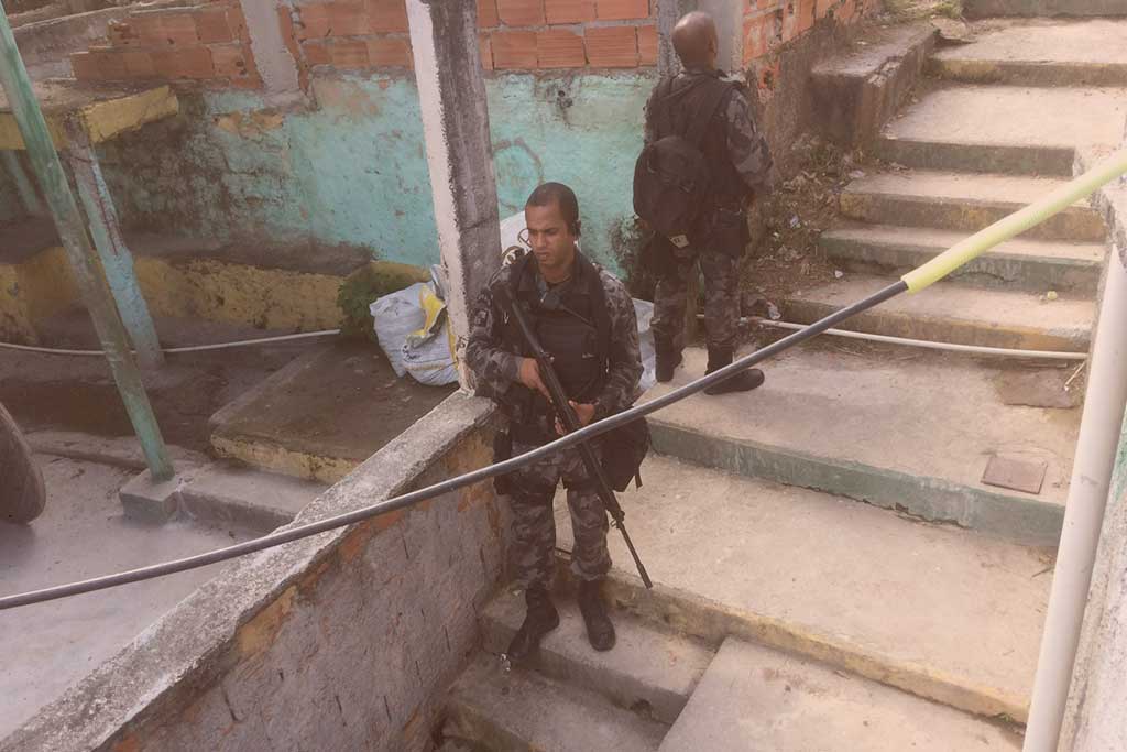 Armed police stand on steep steps between shantytown dwellings