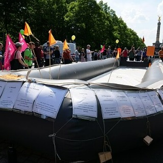 A boat used for smuggling migrants is paraded in a protest. Death notices of dead migrants are attached to the side