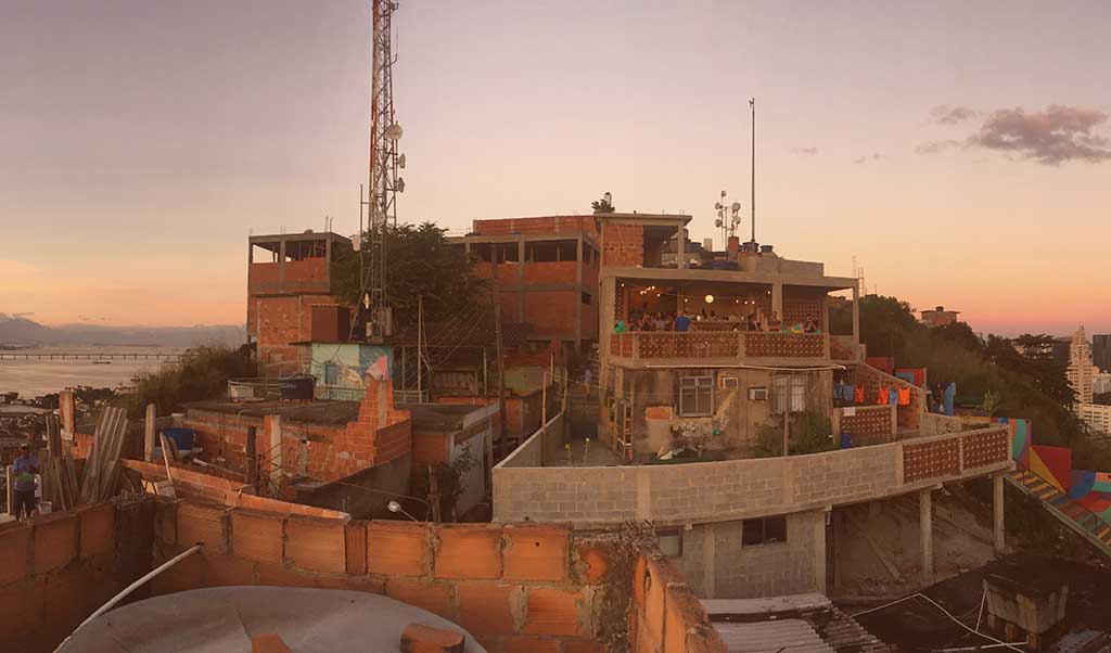 A group of buildings jostle together at the summit of a hill in a city.