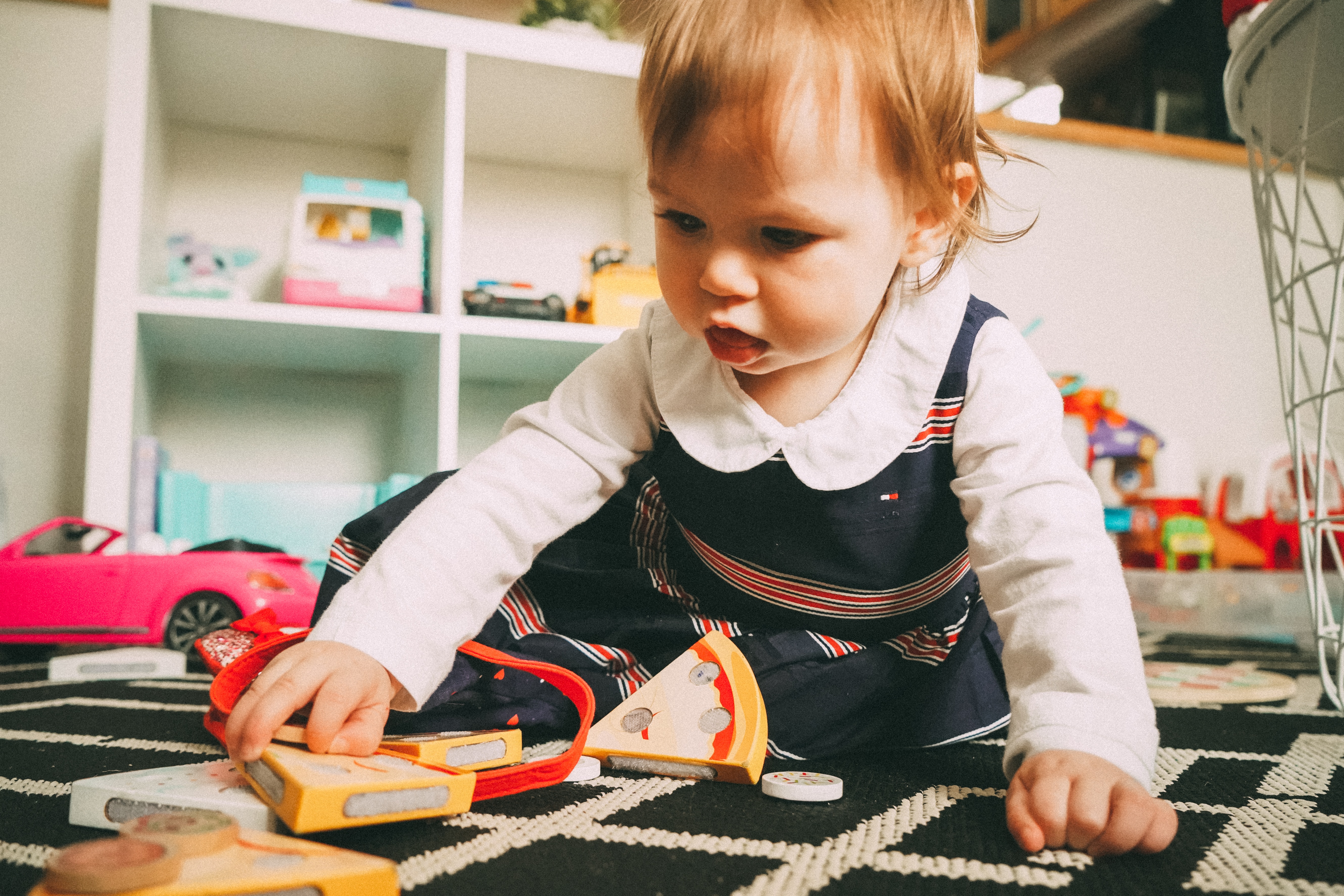 A baby plays with wooden toys on a carpert.