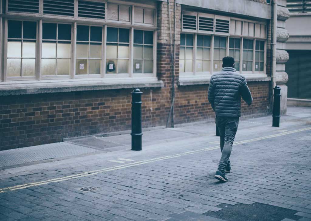 A man walks away down a drab street