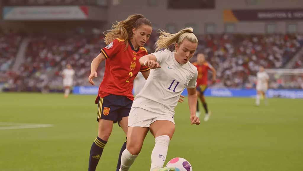 Two footballers run in step as one tries to tackle the other