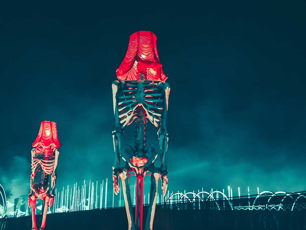 A montage shows skeletons with lamp shades instead if heads beside a fence-like division.