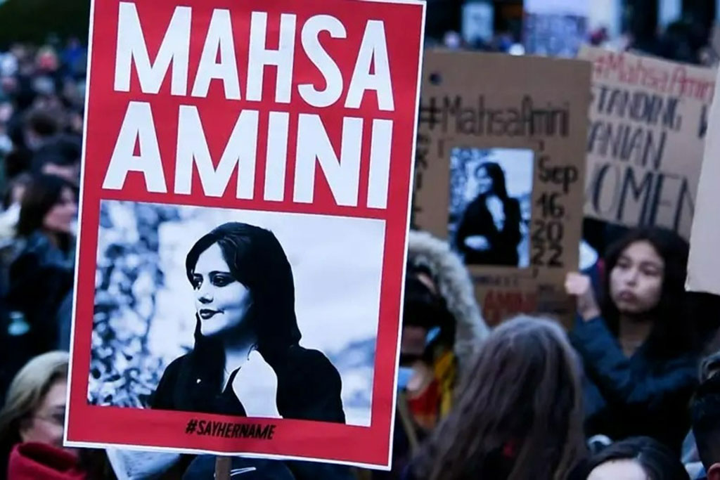 A protester holds a red placard bearing the name and image of Mahsa Amini