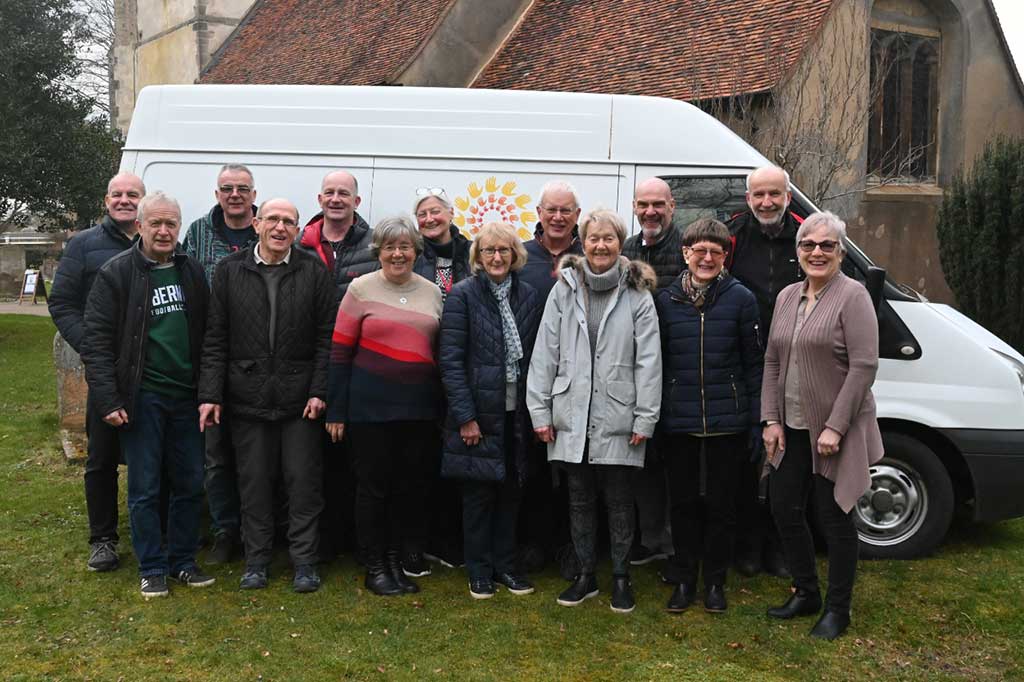 A group of people stand in front of the side of a van marked 'Furniture Friends.