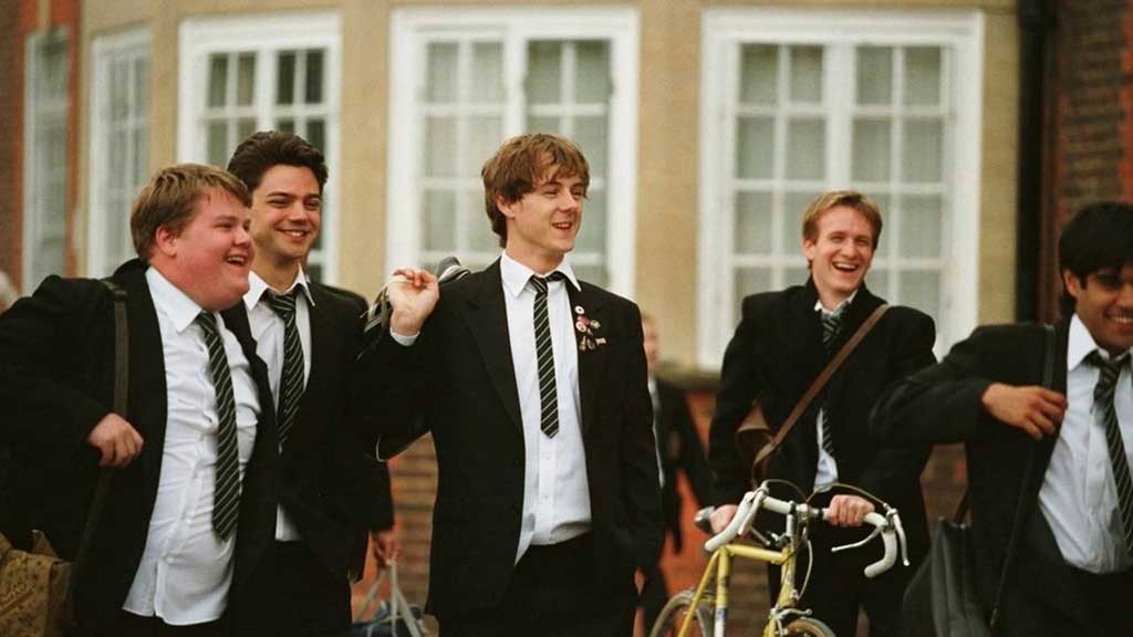 School students walk across a playground confidently talking and laughing with us