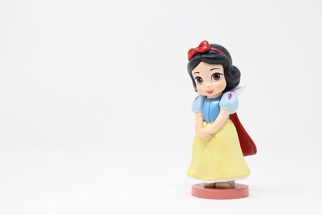 A plastic wind-up Snow White toy stands to the right of the photo, with hands clasped waiting