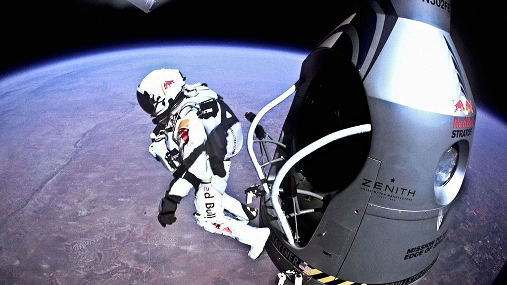 A skydiver in a space pressure shoot leaps from a capsule above the earth.
