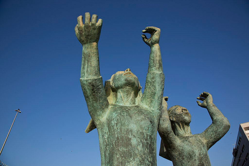 A sculpture shows mourning women raising hands and fists to the sky.