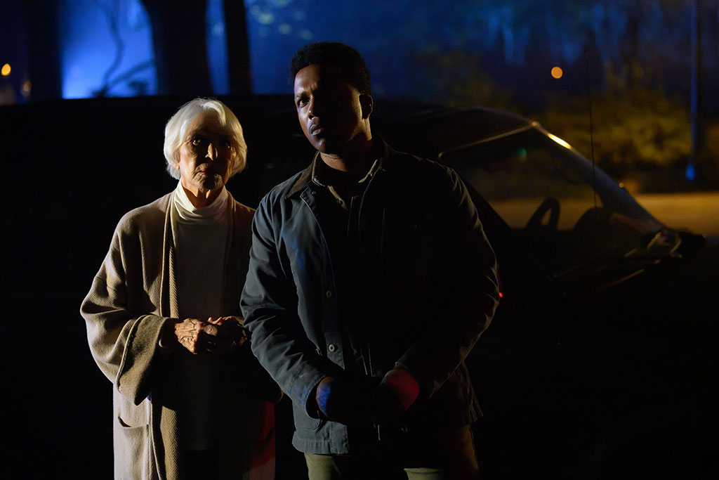 A man and a women stand looking in the same direction with concerned faces.