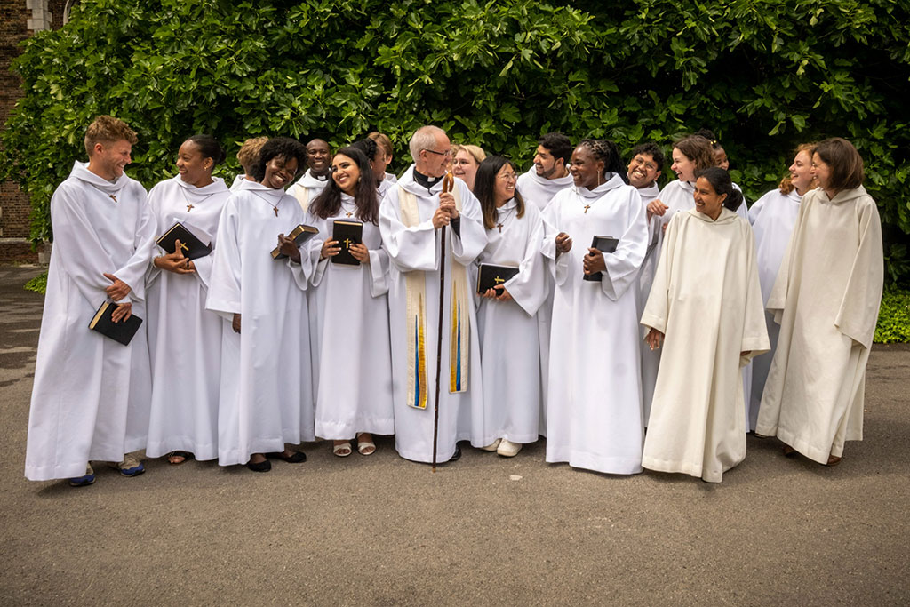 A group of young people wearing white habits stand and laugh with each other.