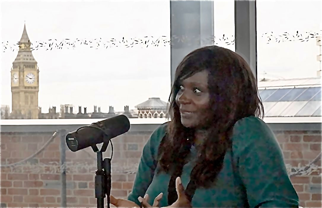 A women sits in beside a microphone taking.