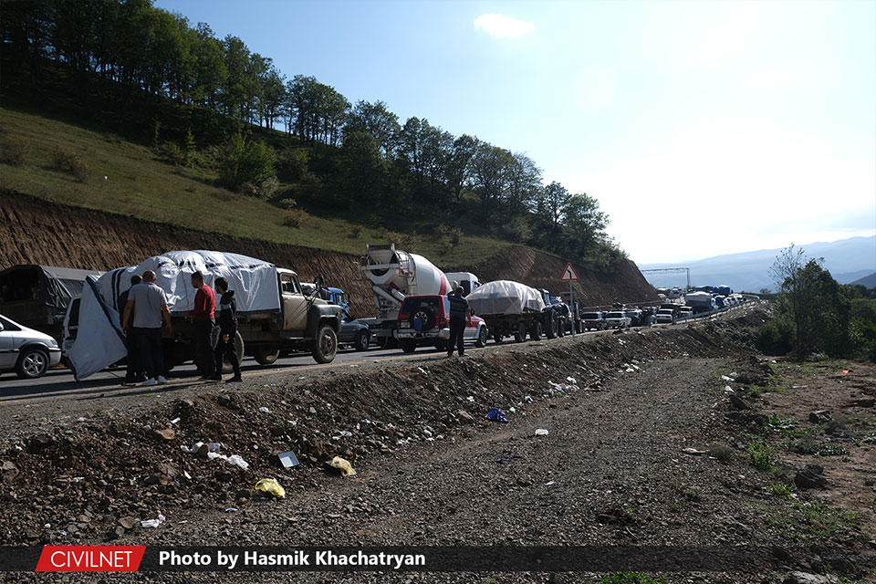 A hillside road blocked by stationary vehicles.