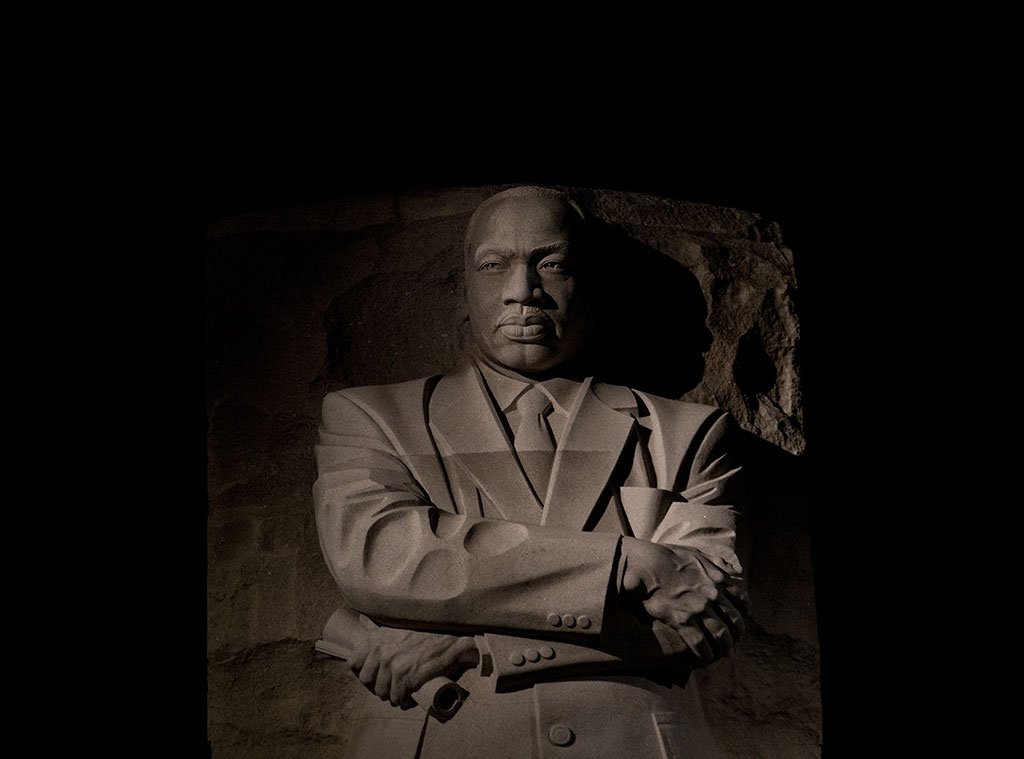 An imposing stone statue of Martin Luther King standing with his arms crossed.