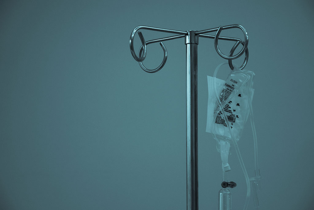 A IV drip bag hangs from a medical stand.