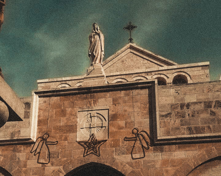 A church gable featuring a cross, a Madonna and angel Christmas decorations.