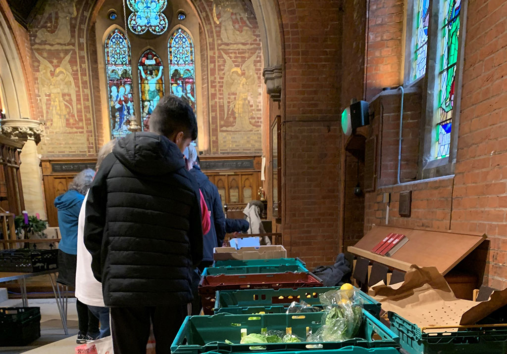 clients of a charity queue beside a table of suppliers in a church