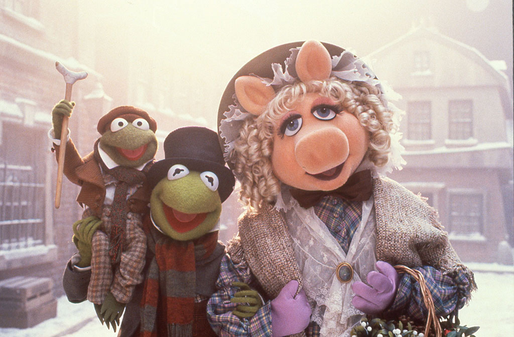 Muppet characters dressed as Dickensian characters stand in a snowy street.