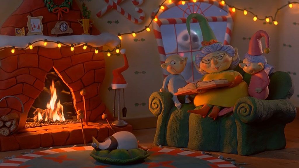 An animated scene shows a grandmother readng a story to children on her lap in front of a fire. 