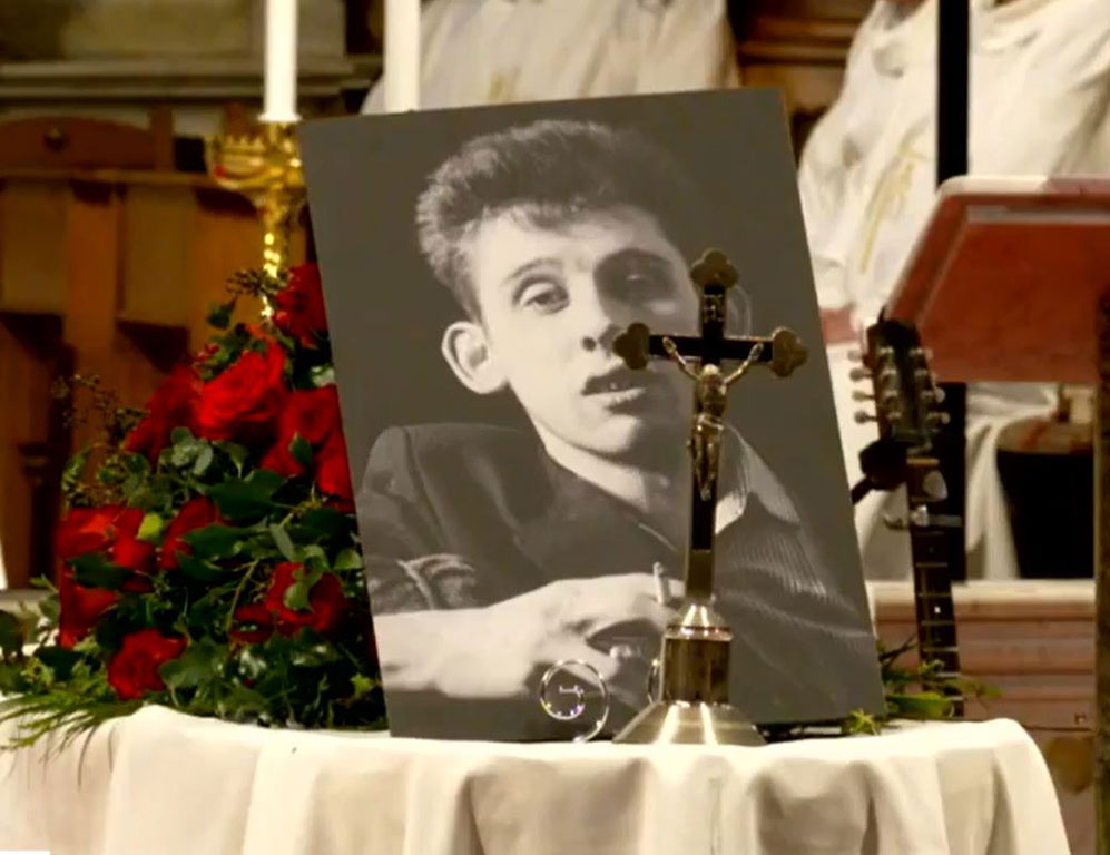 Upon his draped coffin, a picture of Shane MacGowan and a crucifix sit