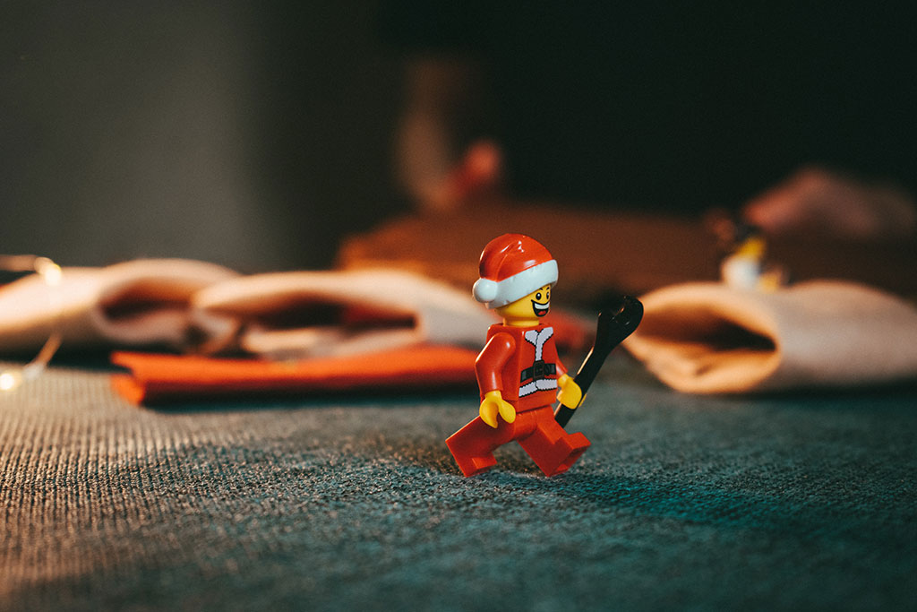 A Lego Stanta figure strolls across a table holding a wrench