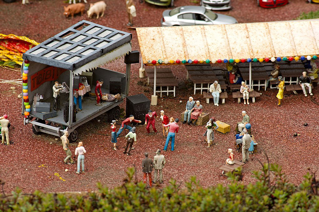 A miniature tableau depicts a band performing at a concert as people dance and others watch from a marque.