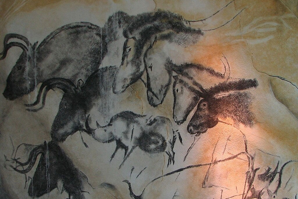 A cave wall drawing of wild animals galloping across other images of themselves.