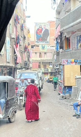 A woman walks through a narrow crowded street.