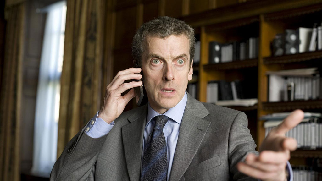 An irate man holds a mobile phone to his ear while gesticulating with his other hand.