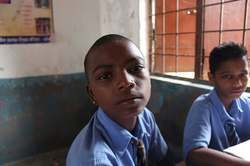 A pupil in a classroom looks around and into the camera.