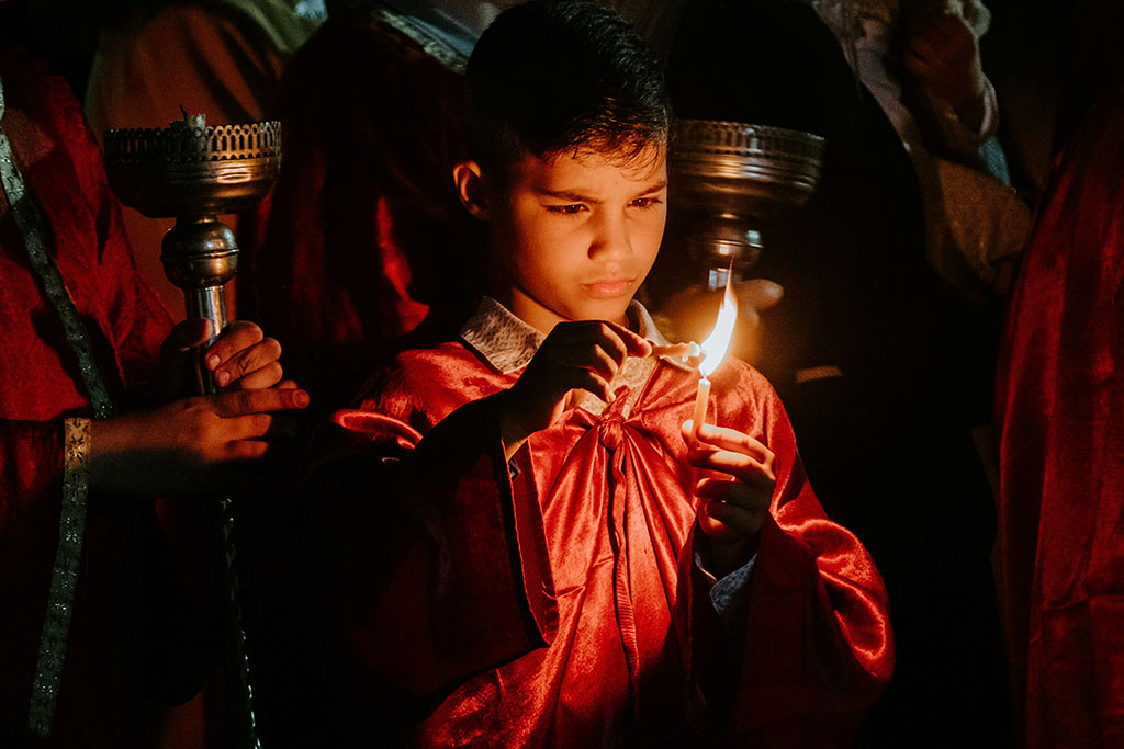 A boy concentrates hard as he holds one candle to another to light it.