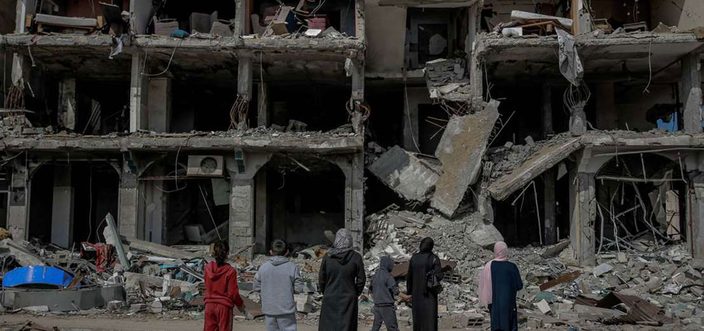 A family look at the concrete shell and remains of a bombed building.