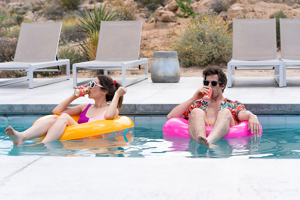 A young couple lounge on floating rings in a swimming pool.